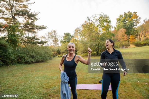 cheerful female friends relaxing after outdoor fitness class - training grounds stockfoto's en -beelden