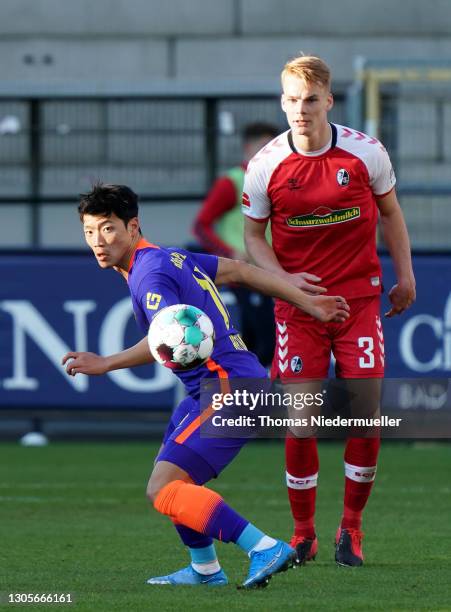 Hwang Hee-chan of RB Leipzig is watched by Philipp Lienhart of SC Freiburg during the Bundesliga match between Sport-Club Freiburg and RB Leipzig at...