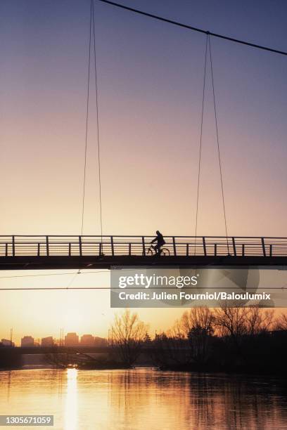 silhouette of a cyclist passing over a bridge, above the loire. - indre y loira fotografías e imágenes de stock