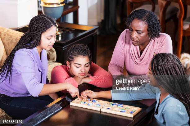 moeder en drie tienerdochters die bordspel spelen - mancala stockfoto's en -beelden