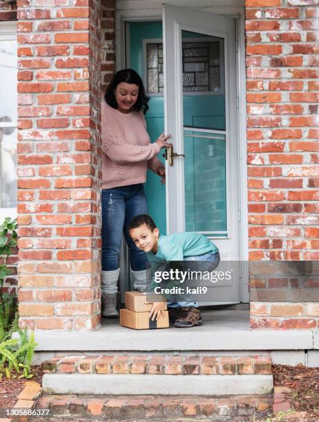 boy helps mother get boxes delivered, left on doorstep - picking up mail stock pictures, royalty-free photos & images