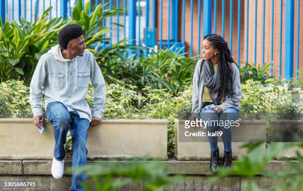 young man and woman, social distance, holding face masks - social distancing friends stock pictures, royalty-free photos & images