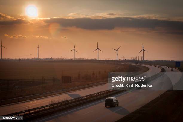 autobahn at sunset with wind turbines in the background, saxony, germany - saxony stock pictures, royalty-free photos & images