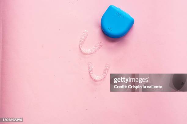 teeth appliance and blue sleeve on pink background - invisalign stock pictures, royalty-free photos & images