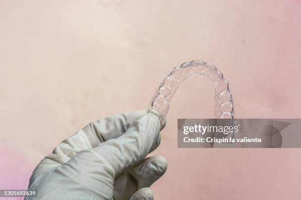 woman's hand with gloves holding an invisible orthodontics - invisalign stock pictures, royalty-free photos & images