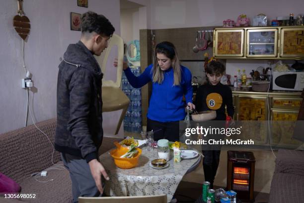 Year old, Eisa Qais Hadi his sister Maryam Qais Hadi , and brother Yousef who fled Qaraqosh in 2014, prepare dinner in their temporary house which...