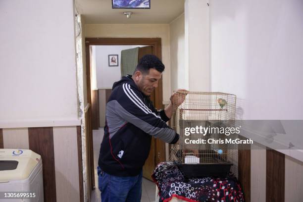 Allah Hanah Shaba, who fled his home in Bartella in 2014, feeds his birds in his temporary home on the empty fourth floor of a shopping mall on March...