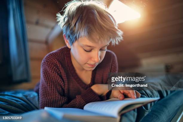 tiener die een boek op het bed leest - tweenies stockfoto's en -beelden