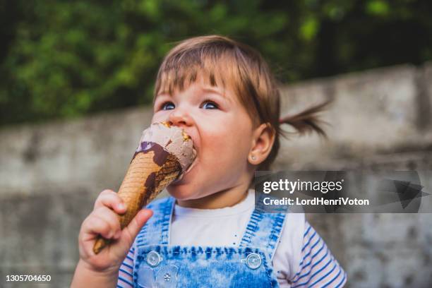 small toddler girl eating ice cream - girl eating messy ice cream cone stock pictures, royalty-free photos & images