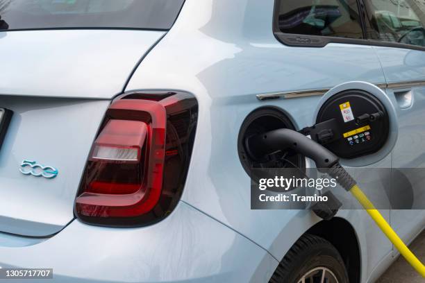 small car on a public charging point on a street - fiat stock pictures, royalty-free photos & images