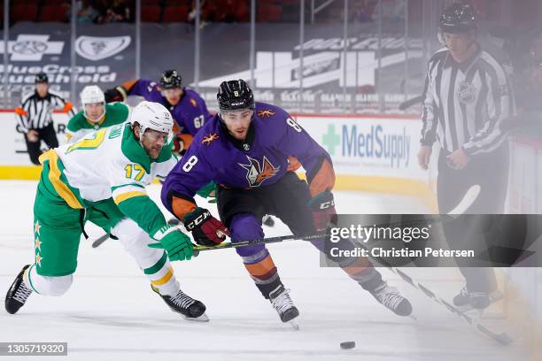 Nick Schmaltz of the Arizona Coyotes skates with the puck under pressure from Marcus Foligno of the Minnesota Wild during the first period of the NHL...