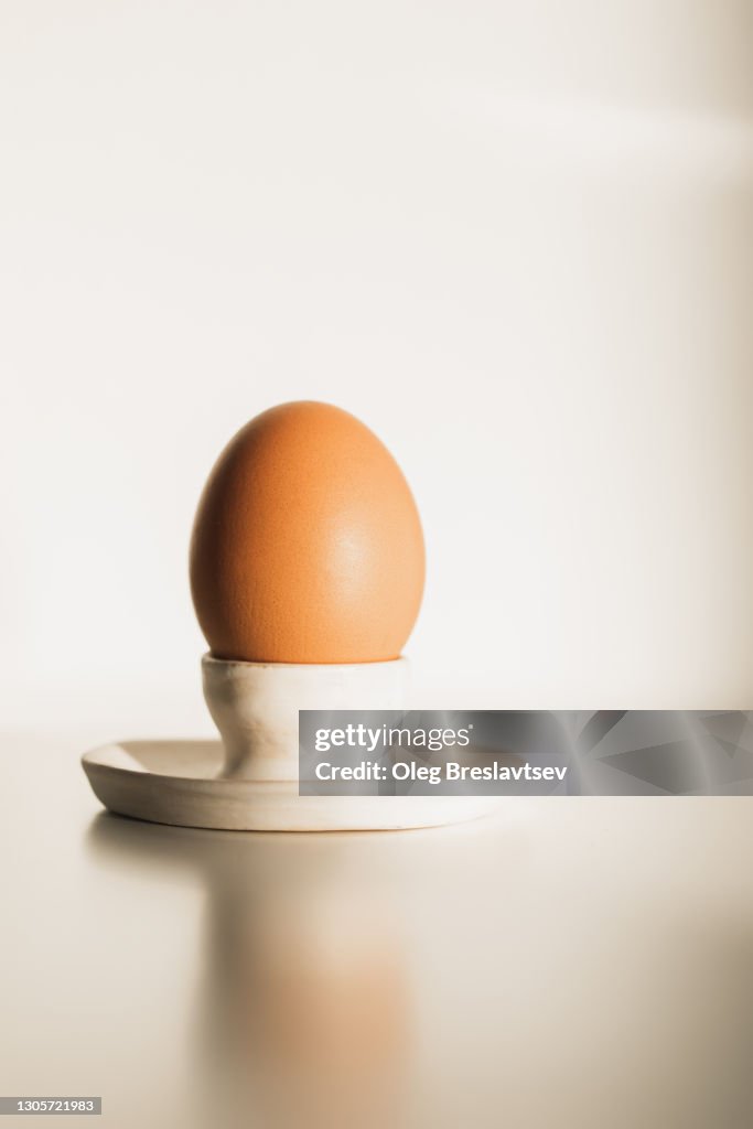 One egg in ceramic egg-Cup holder on light white background with beautiful sunlight