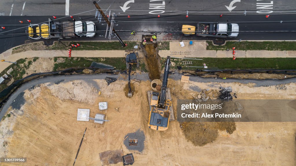 Excavator working on the construction site at the first stage of the earthwork, nearby a road.