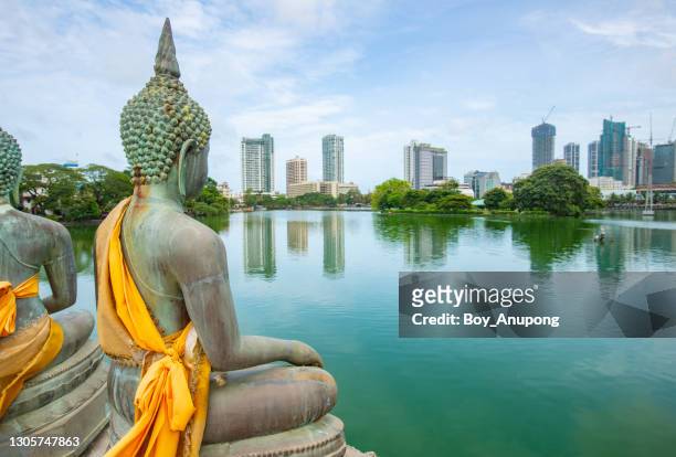 the buddha statue in seema malaka temple on beira lake with beautiful view of colombo skyline in colombo cbd. - colombe stock-fotos und bilder
