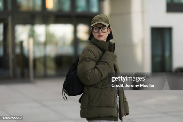 Maria Barteczko wearing green puffer Zara jacket, grey H&M sweater, black Prada nylon backpack, green nylon Zara baseball cap and black oversized...