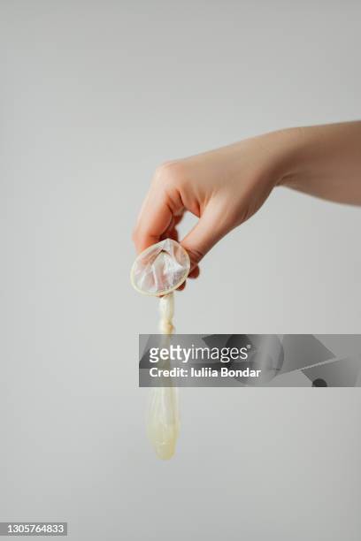 hand holding a used condom - condon fotografías e imágenes de stock