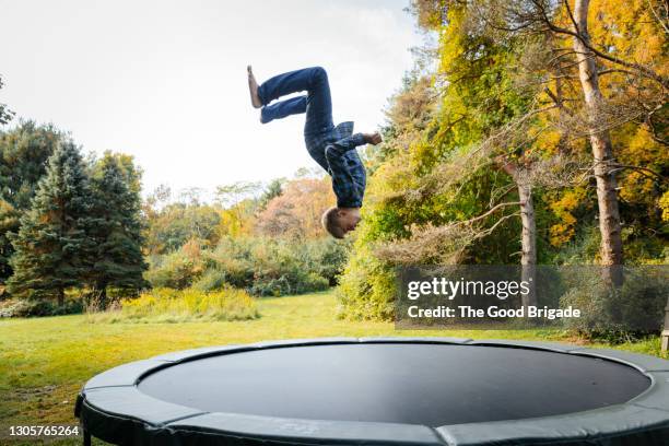 full length of boy jumping on trampoline at backyard - backflipping imagens e fotografias de stock