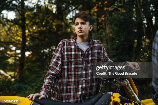 thoughtful teenage boy standing with motor bike - boy thinking stock-fotos und bilder