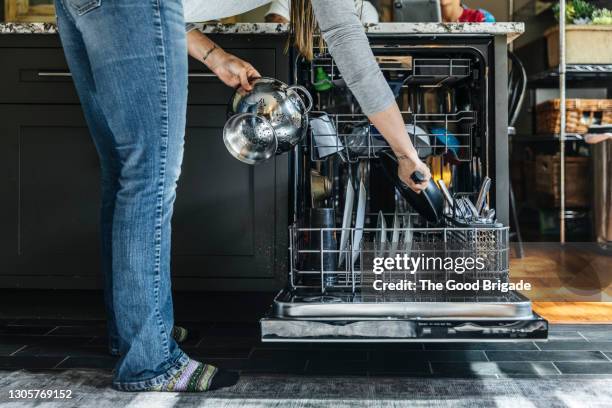 woman arranging utensils in dishwasher at home - spülmaschine stock-fotos und bilder