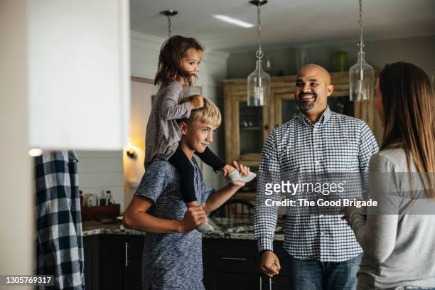 happy parents looking at boy carrying girl on shoulder - blended family stockfoto's en -beelden