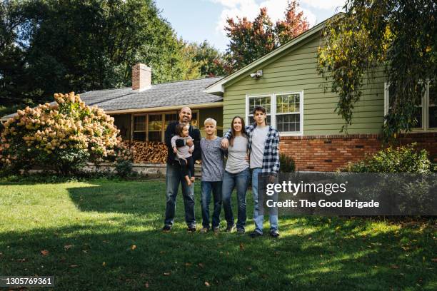 portrait of blended family standing in front yard at home - family in front of house stock-fotos und bilder