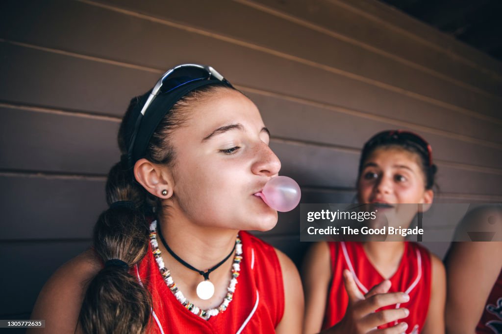 Teenage girl bowing bubble in softball dugout