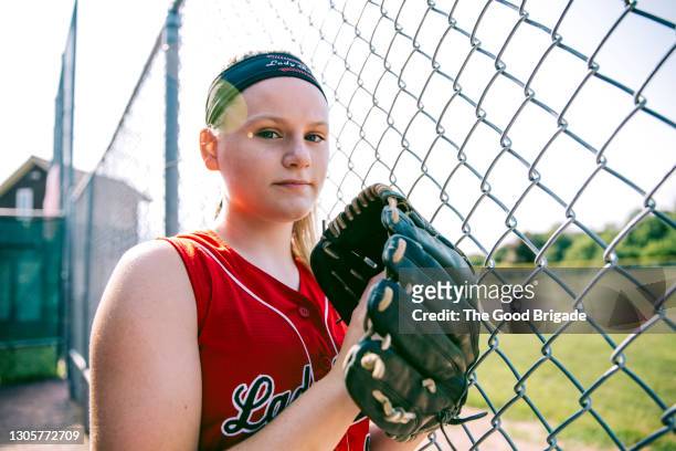portrait of confident softball player holding glove in dugout - sports dugout fotografías e imágenes de stock
