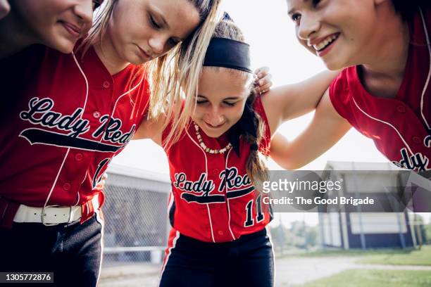girl's softball team huddling on field before game - softball sport stock-fotos und bilder
