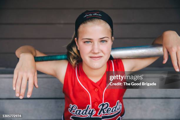 portrait of teenage softball player holding baseball bat behind head - softball sport stock-fotos und bilder