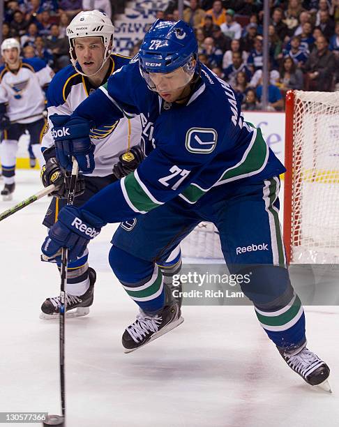 Manny Malhotra of the Vancouver Canucks controls the loose puck in the corner while Kent Huskins of the St Louis Blues looks on during the second...