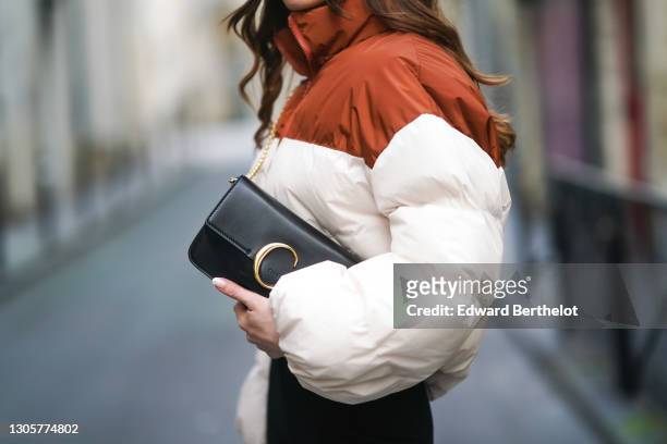 Marine Blanpain wears an oversize winter turtleneck puffer bi-color orange/brown and white jacket from Nastygal, a black leather Chloe bag, on...