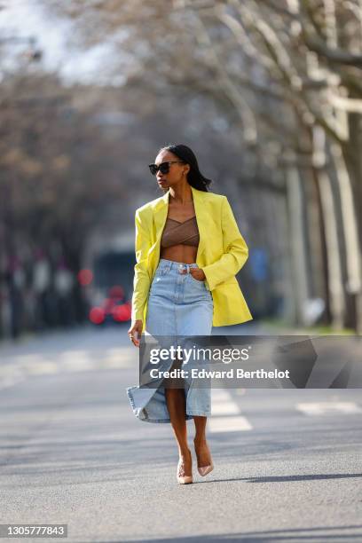 Emilie Joseph aka "in_fashionwetrust" wears sunglasses, a neon yellow oversized blazer jacket from Zara Menswear, brown bras / crop top from Mango, a...