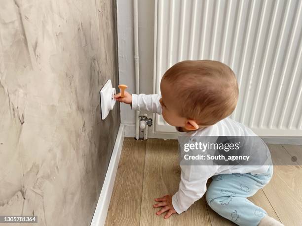 baby boy reaching for a plug socket - plug socket stock pictures, royalty-free photos & images