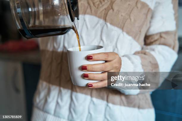 woman pouring herself hot coffee to a mug at home. - koffiepot stockfoto's en -beelden