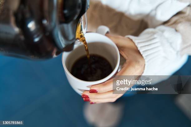 woman pouring herself hot coffee to a mug. - drinking stockfoto's en -beelden