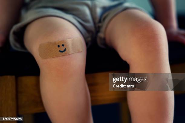 child with a plaster on knee - pleister bouwmateriaal stockfoto's en -beelden