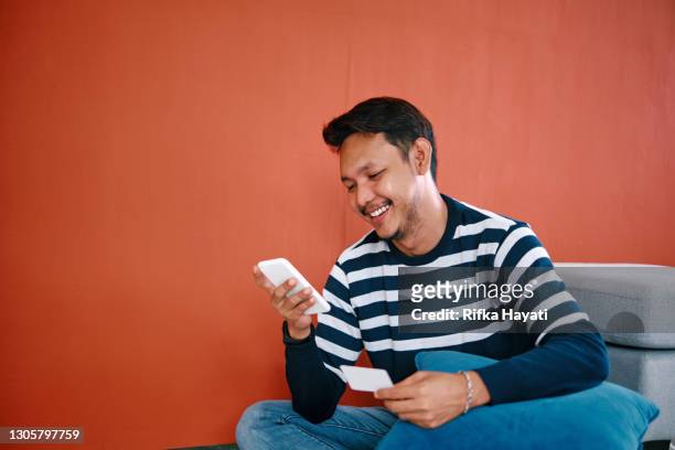 man shopping using phone with credit card - malay archipelago stock pictures, royalty-free photos & images