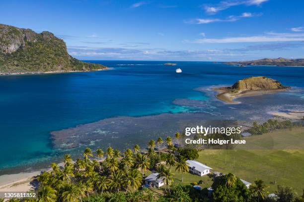 aerial of village school with cruise ship mv reef endeavour (captain cook cruises fiji) in the distance - fiji cruise stock pictures, royalty-free photos & images