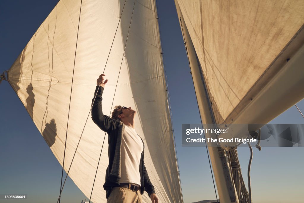 Man looking up at sails while standing on boat