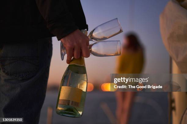 rear view of man holding champagne flutes and bottle on sailboat at dusk - シャンパン ストックフォトと画像