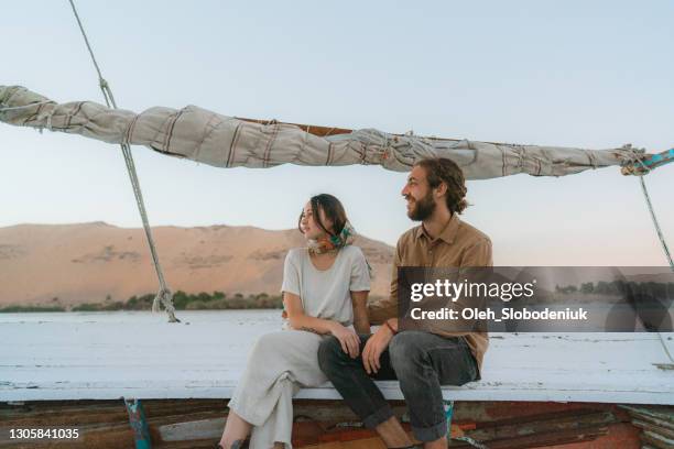 young heterosexual couple traveling on felucca on the nile at sunset - felucca boat imagens e fotografias de stock