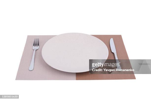 dinner place setting. a china plate with silver fork and knife on placemat, isolated on white background - カトラリー ストックフォトと画像