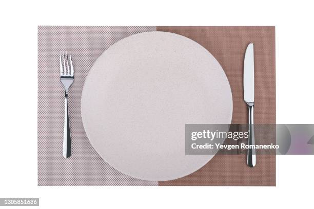 dinner place setting. a china plate with silver fork and knife on placemat, isolated on white background - jogo americano imagens e fotografias de stock