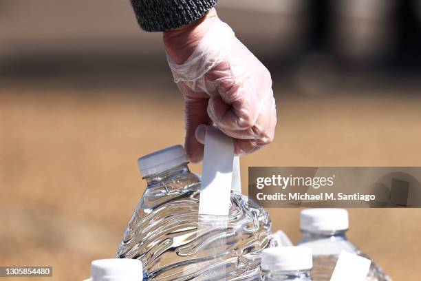 Volunteer grabs a gallon of water at a water and food distribution drive held by College Hill Baptist Church and the World Central kitchen on March...