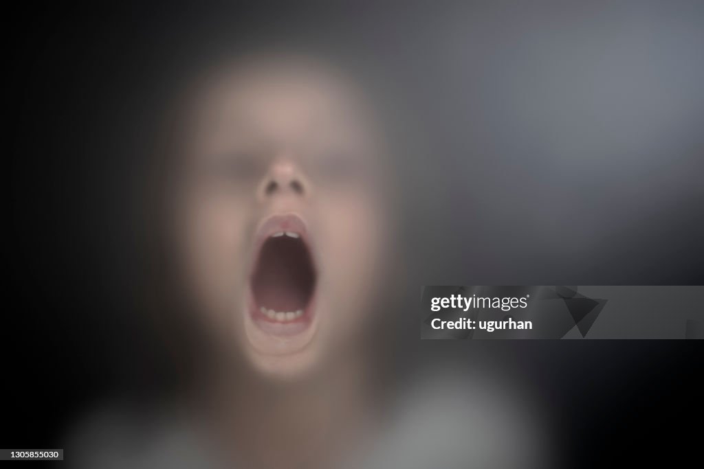 View of scared child through frosted glass