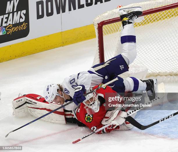 Blake Coleman of the Tampa Bay Lightning falls over Kevin Lankinen of the Chicago Blackhawks after taking a shot at the United Center on March 07,...