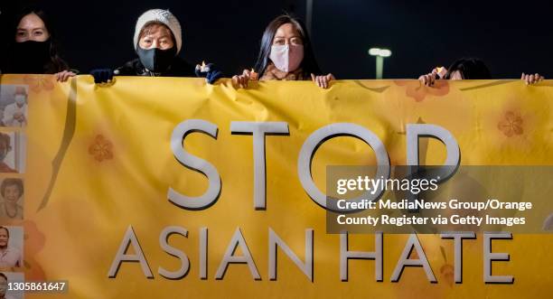 Linda Nguyen, right, a victim of Asian hate, joins members of the Vietnamese community and others hold up a banner against Asian hate during a...