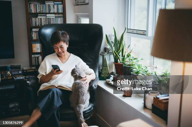 senior asiatisk kvinna som använder en smartphone - person on phone at home bildbanksfoton och bilder
