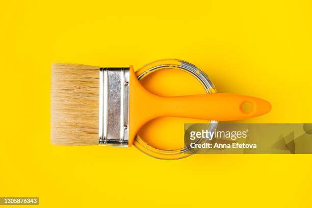one clean paintbrush places on metal futuristic gray jar with bright yellow paint for renovation works on illuminating yellow background. flat lay style. copy space for your design. concept of redecoration in home interior. color swatch for design ideas. - monochrome yellow stock pictures, royalty-free photos & images
