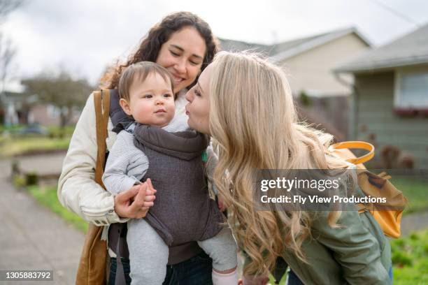 loving mom giving cute toddler girl a kiss while outside walking in neighborhood - asian lesbians kiss stock pictures, royalty-free photos & images